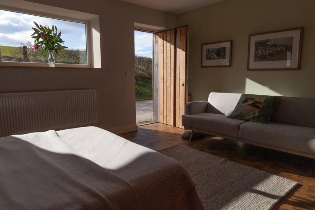 ein Wohnzimmer mit einem Bett, einem Sofa und einem Fenster in der Unterkunft "The Studio" Contemporary studio with organic swimming pool in Skelsmergh