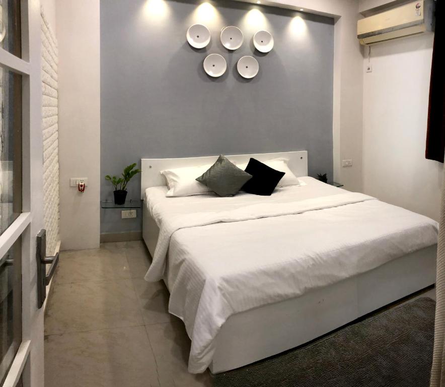una camera da letto con letto, lenzuola e cuscini bianchi di House 44 2BHK a Greater Noida