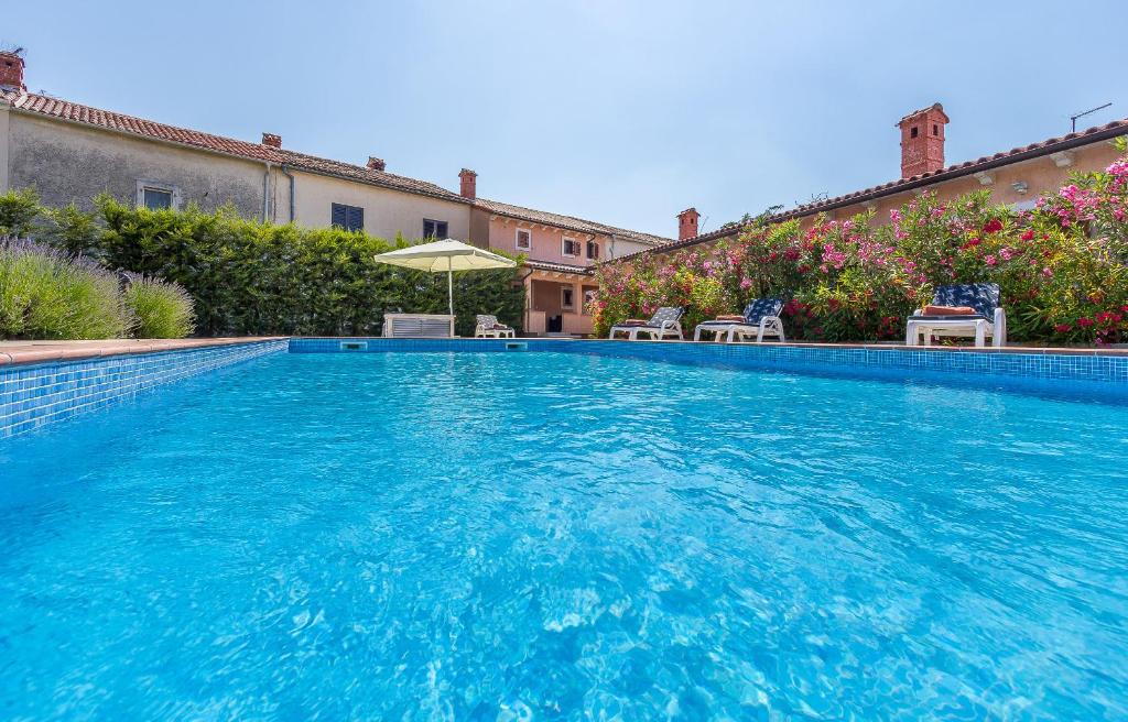 a large blue swimming pool with chairs and an umbrella at Pool & Sun Villa Rici in Loborika