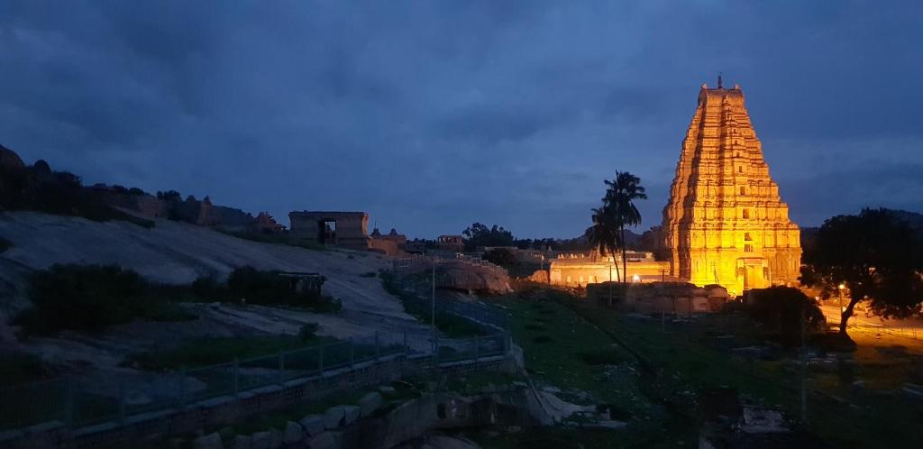 a large building with a lit up tower at night at Padma Guest House in Hampi