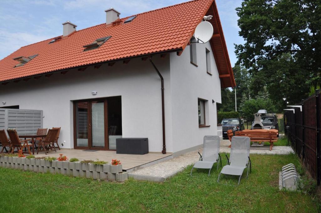 a white house with a deck and a table and chairs at Willa Słoneczna in Sztutowo