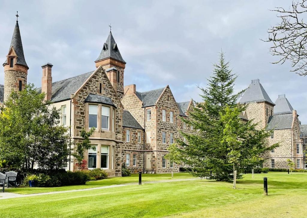 un gran edificio con un patio de césped delante de él en No 49 a spacious executive apartment in Inverness, en Inverness