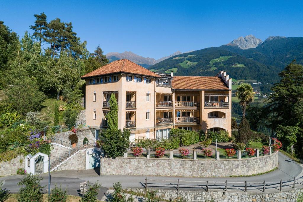 a building on a hill with mountains in the background at Appartementhaus Am Waalweg in Rifiano