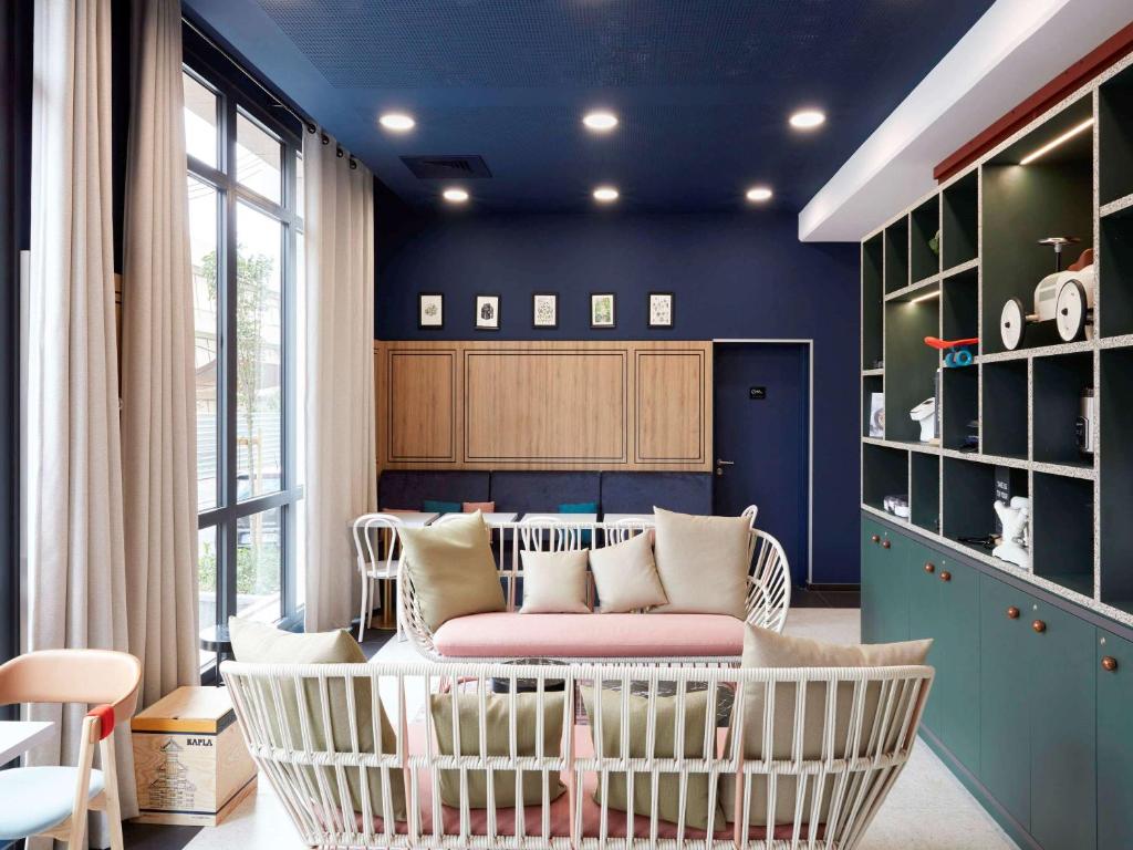 Cette chambre aux murs bleus dispose d'un canapé et de chaises. dans l'établissement Aparthotel Adagio Paris Suresnes Longchamp, à Suresnes