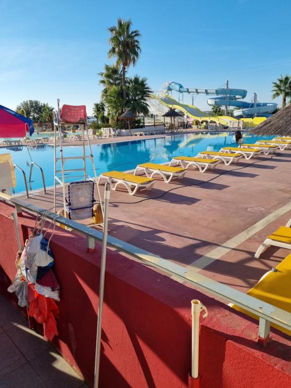 une grande piscine avec des chaises longues jaunes et blanches dans l'établissement marie & cyrille, à Lattes