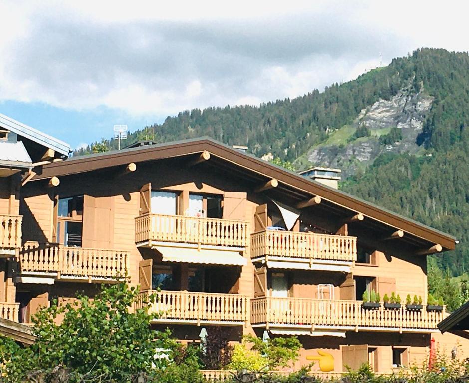un grand bâtiment en bois avec balcon et montagne dans l'établissement Le Nantoran, à Praz-sur-Arly