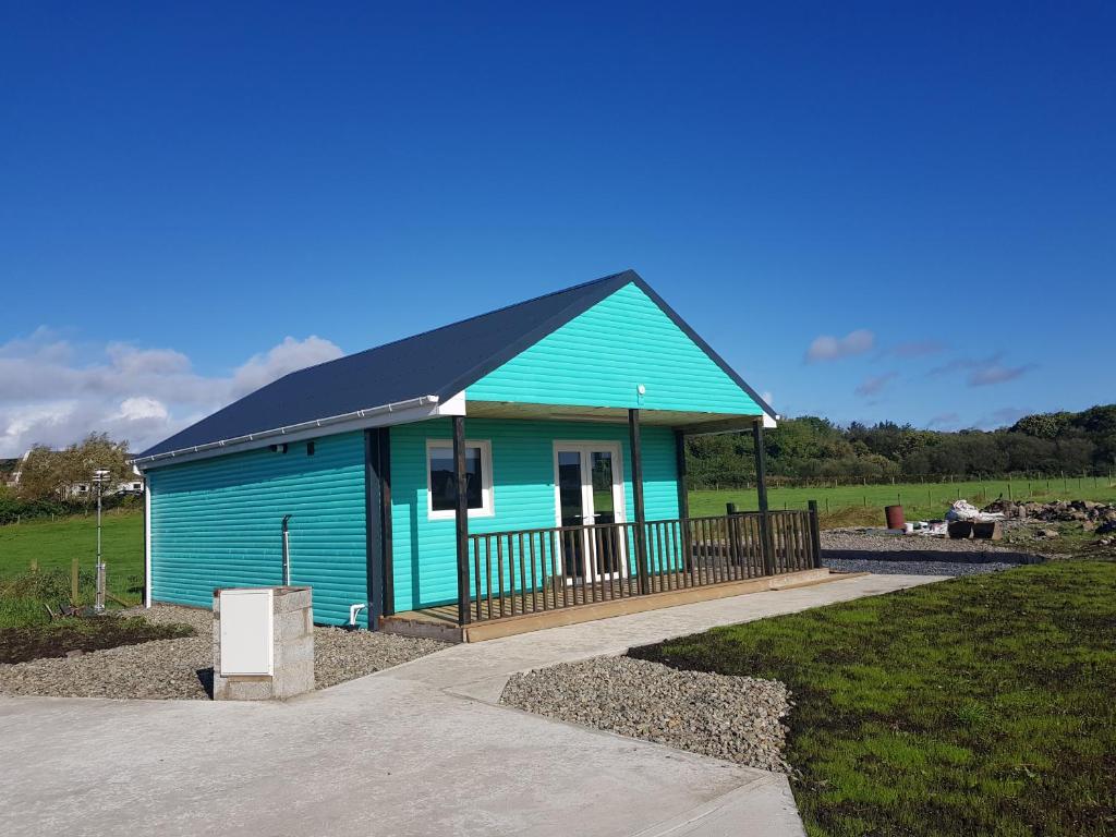 卡爾達夫的住宿－Crag Na Cor Log Cabin，一座蓝色的建筑,在田野上设有黑色屋顶