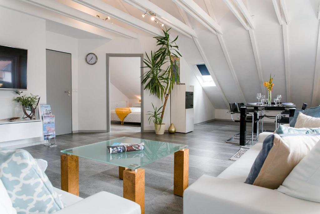 ein Wohnzimmer mit weißen Möbeln und einem Tisch in der Unterkunft Ferienwohnung Fuchs in Bodman-Ludwigshafen