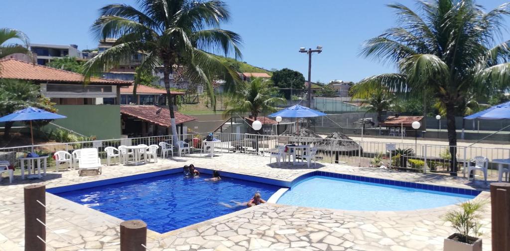 einen Pool in einem Resort mit Leuten darin in der Unterkunft Residencial Marina Club in São Pedro da Aldeia
