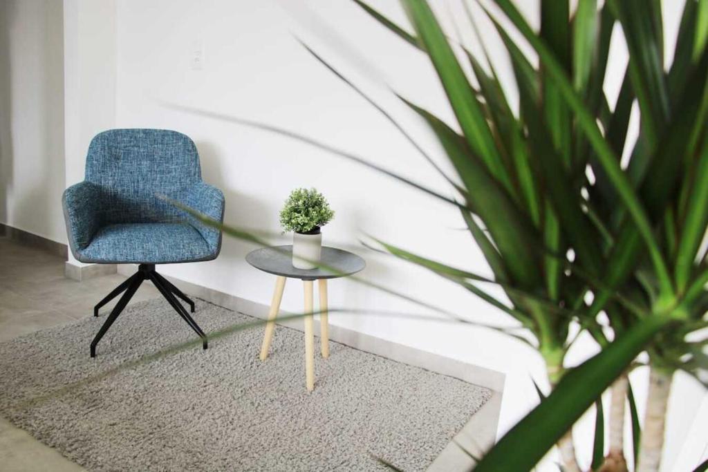 uma cadeira azul e uma mesa com um vaso de plantas em New & Modern Apartment with Beautiful Lake View! em Lugano