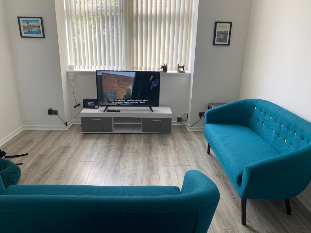 a living room with two blue couches and a television at The Cochno Flat, Clydebank in Dalmuir