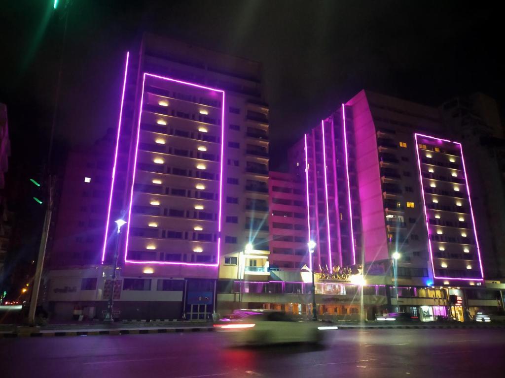 two tall buildings lit up in purple at night at 26th of July Apartments in Alexandria