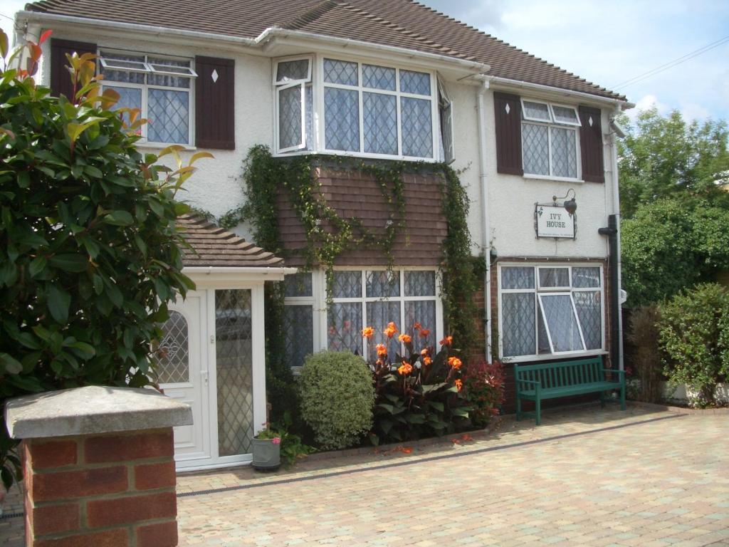 uma casa com um banco verde em frente em Ivy House em Ickenham