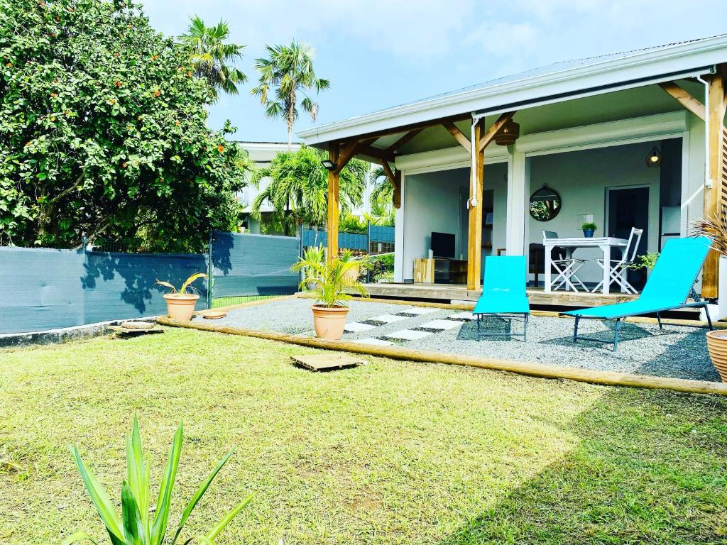 a house with a patio with blue chairs in the yard at Vanille, à proximité des plages, idéalement situé pour visiter la Guadeloupe in Le Gosier