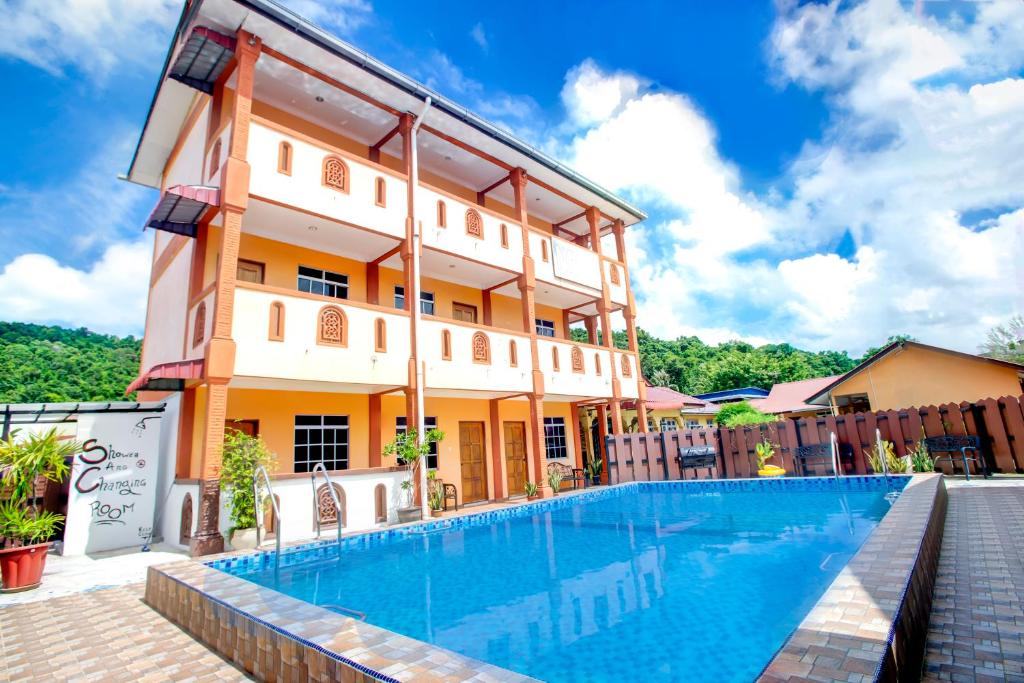 un hotel con piscina frente a un edificio en NR Langkawi Motel en Pantai Cenang