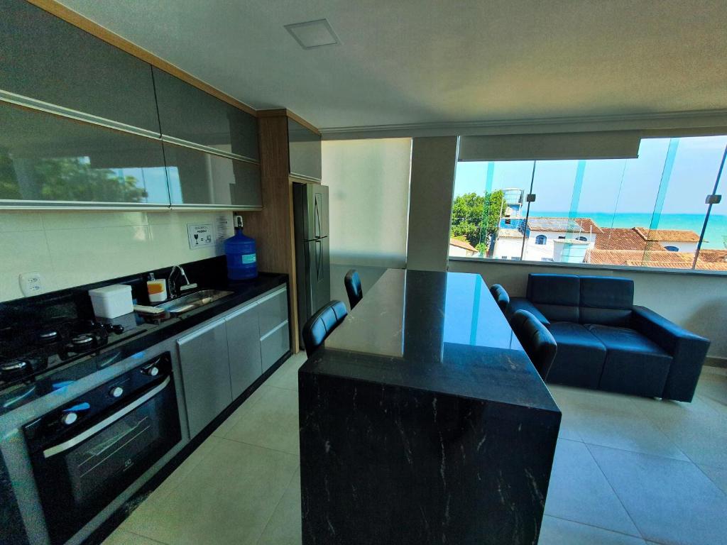 a kitchen with a black counter top and a table at Apartamento Novo em Iriri - Vista para o Mar in Iriri