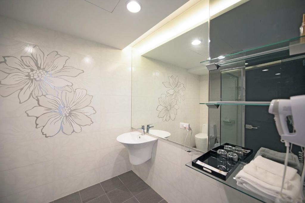 a bathroom with a sink and a toilet with flowers on the wall at 松柏文旅Cypress Inn in Taitung City