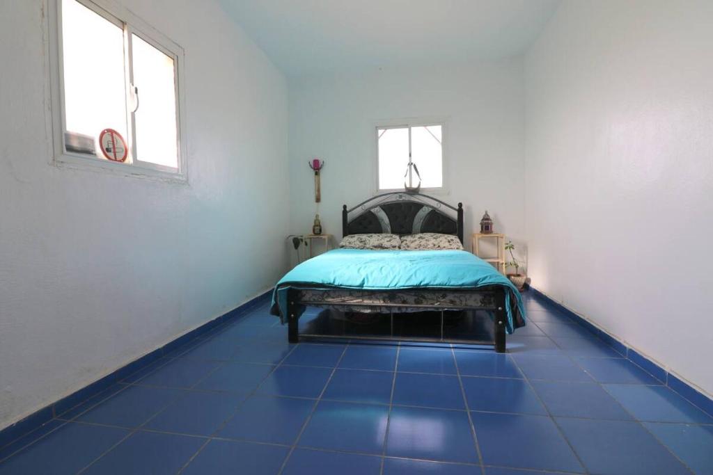 a bedroom with a blue tiled floor with a bed at Ait Mouli Surf House in Safi
