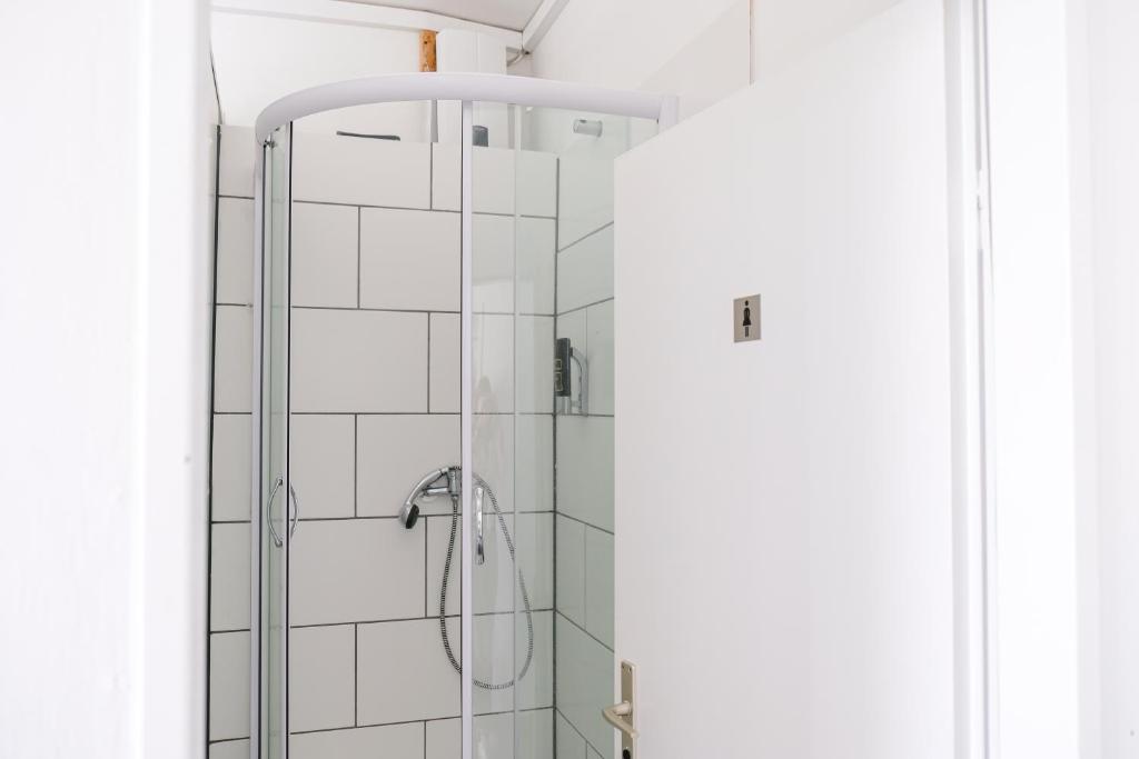 um chuveiro na casa de banho com azulejos brancos em Hammerbrook Hostel em Hamburgo