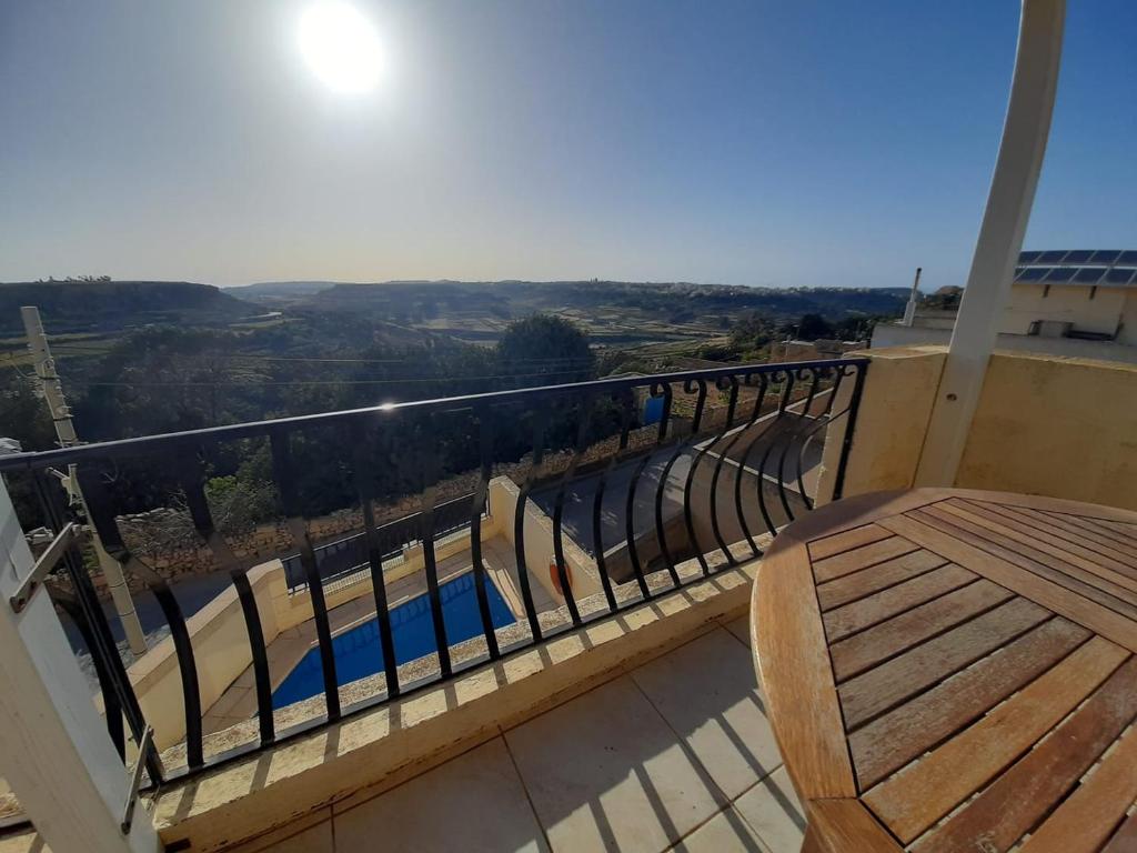 a balcony with a wooden bench with a view at In-Nuffara Farmhouse, Nadur Gozo in Nadur