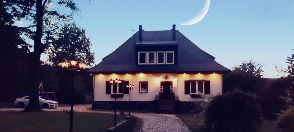 a white house with lights on the front of it at Apartament pod Karpaczem in Miłków