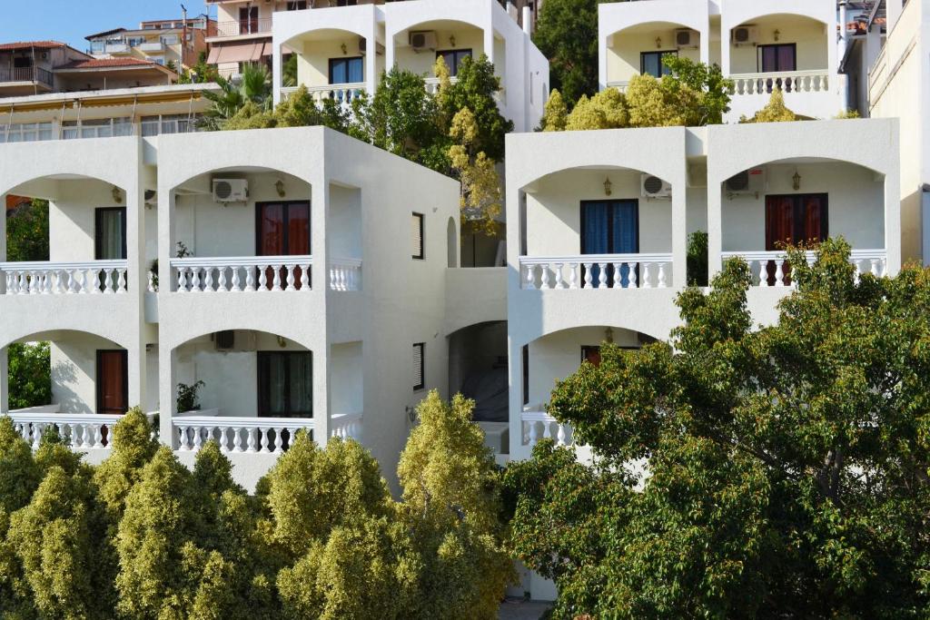 an image of a white apartment building with trees at To Spiti Tis Eirinis in Poros