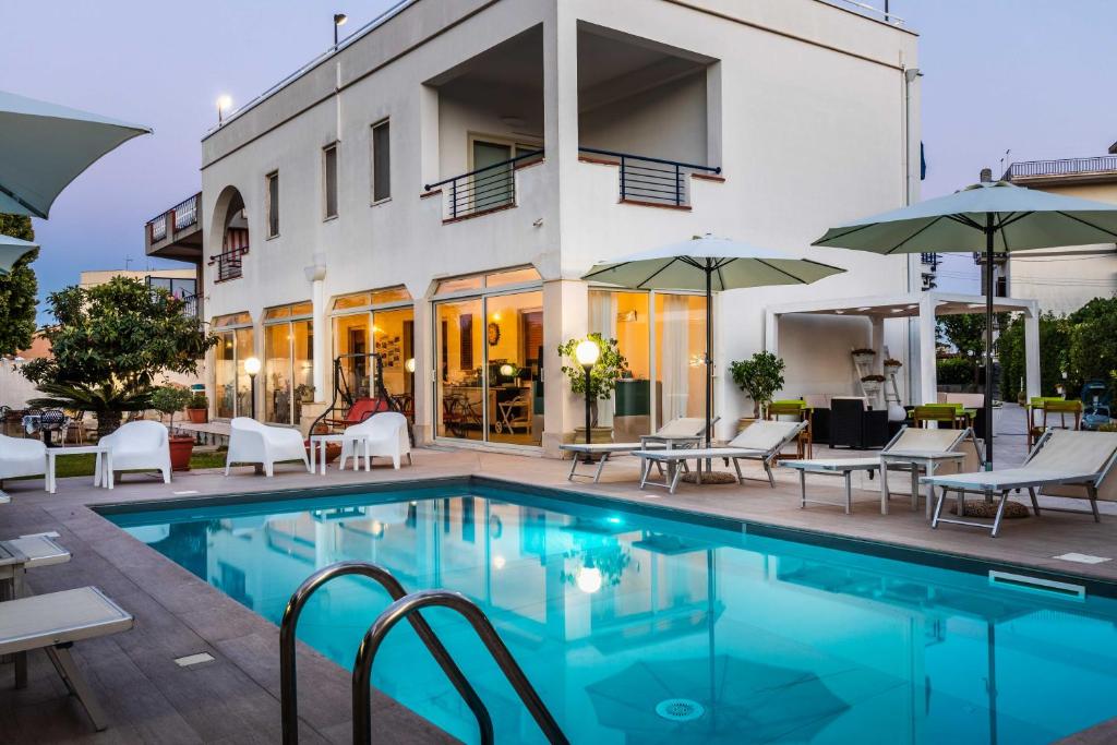 a pool in front of a building with chairs and umbrellas at Marricriu Camere Avola in Avola