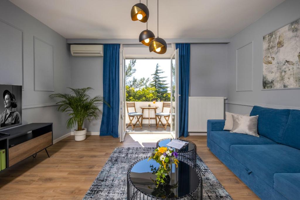 uma sala de estar com um sofá azul e uma mesa em Blue Allure Apartment em Rijeka