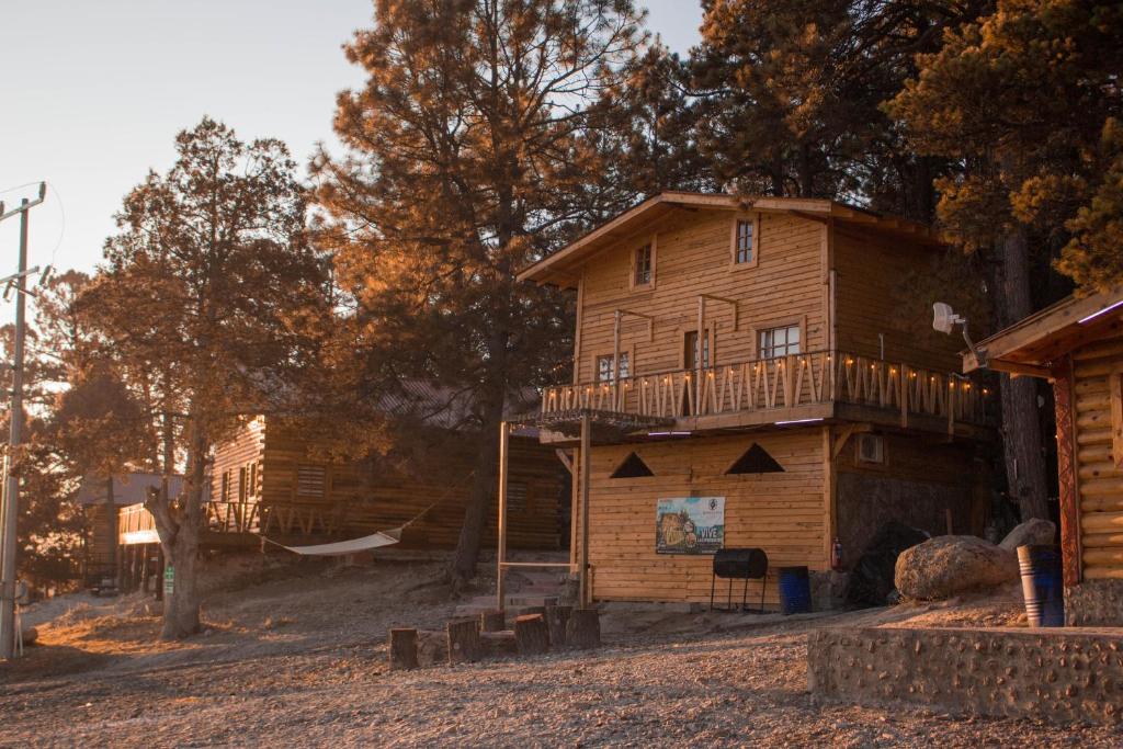 a log cabin with a balcony and a playground at Wooden Inn - Cabañas Boutique y Bubble Glamping en Creel in Creel