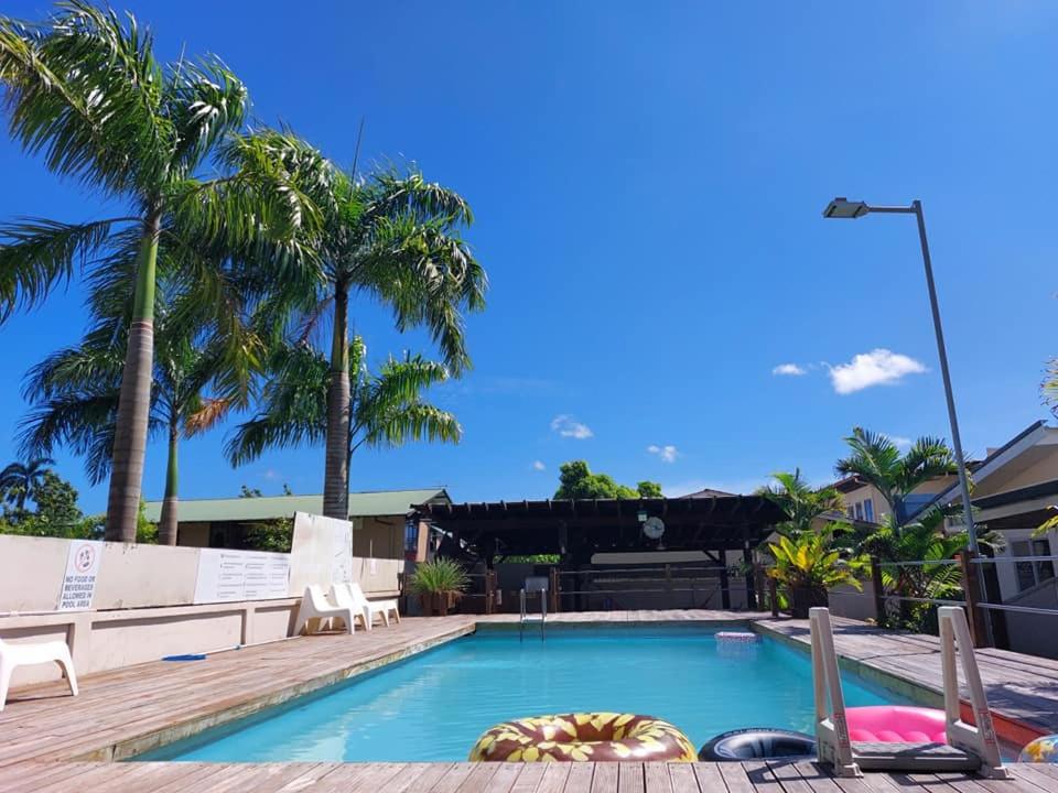 a swimming pool with palm trees in the background at Elementz Apartments in Paramaribo