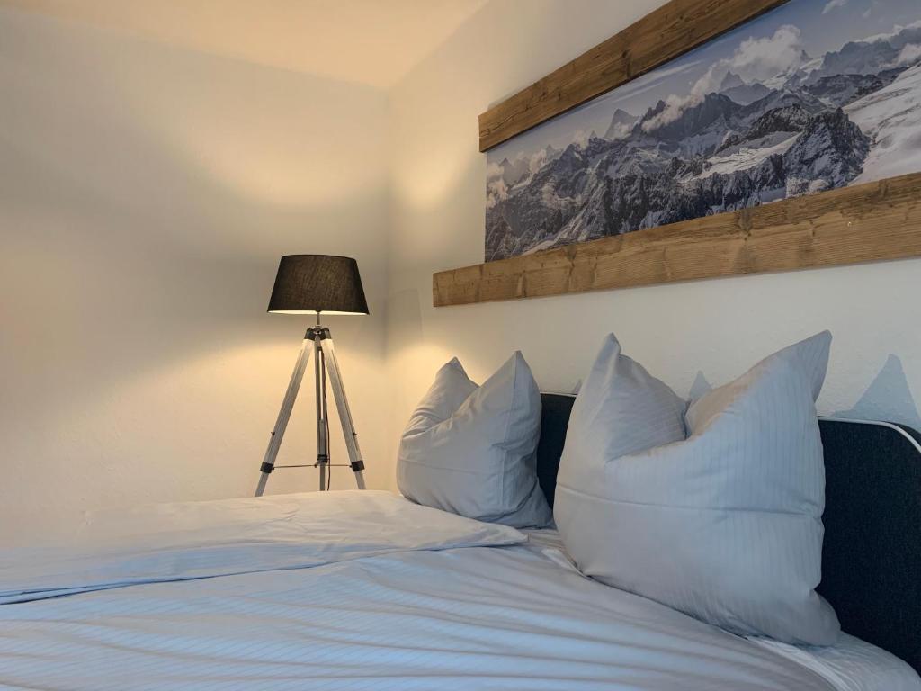 a bedroom with a bed with white pillows and a lamp at Bergsteiger Schlafplätze mit Parkplatz in Haslach