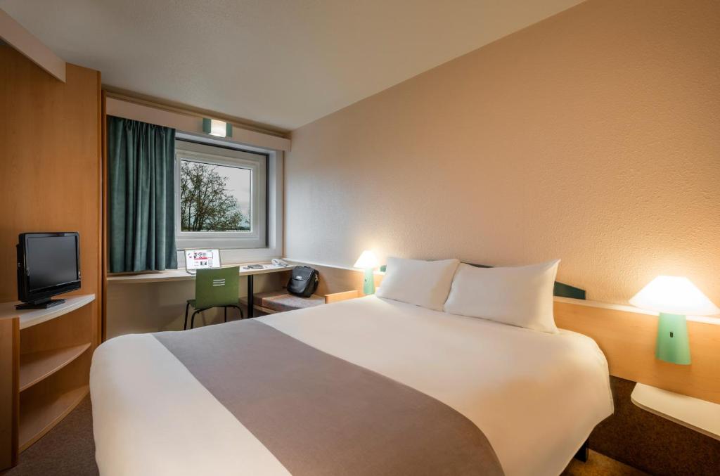 a hotel room with a large bed and a window at ibis Paris Pantin Eglise in Pantin