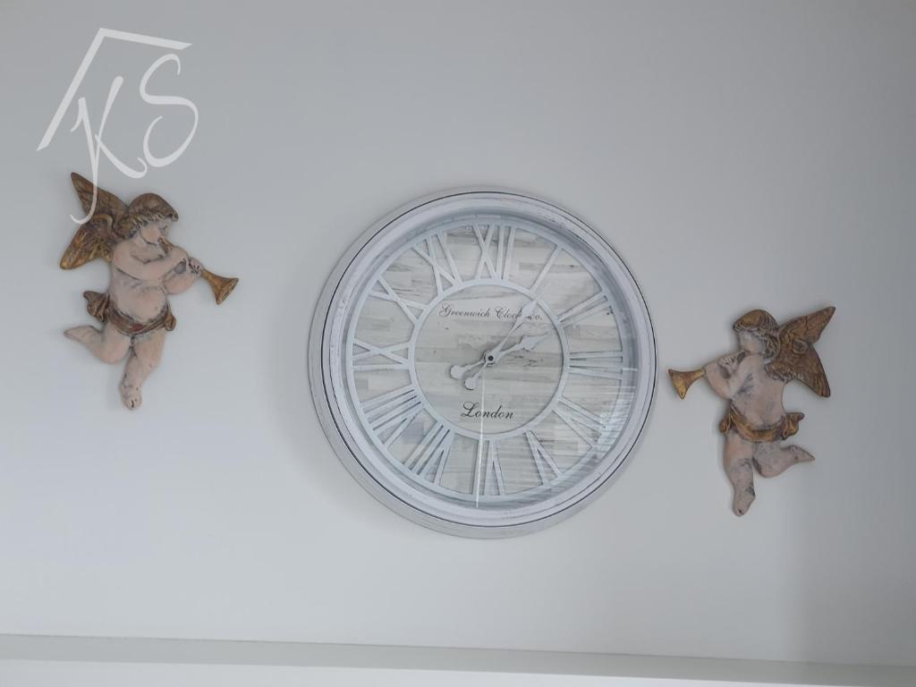 zegar na białej ścianie z dwoma ptakami w obiekcie Amko Style Apartament Pod Aniołami 59 Willa Nord w Jastrzębiej Górze