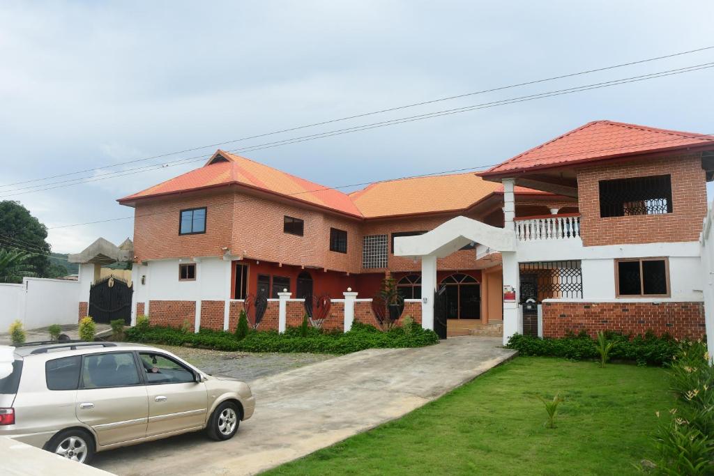 Odo So Royal Hotel في Oko Sombo: منزل فيه سيارة متوقفة أمامه