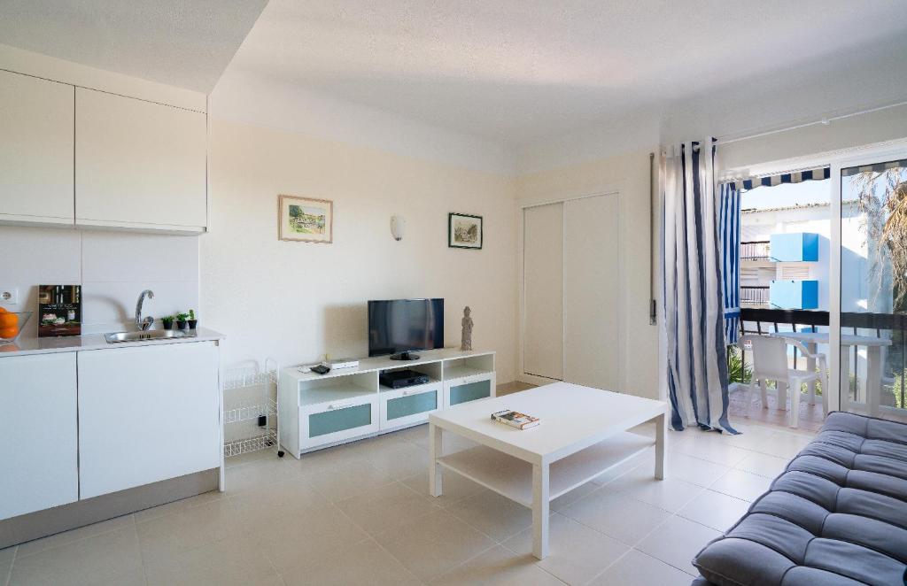 ein Wohnzimmer mit einem Sofa, einem TV und einem Tisch in der Unterkunft Lago Azul 2 in Quarteira