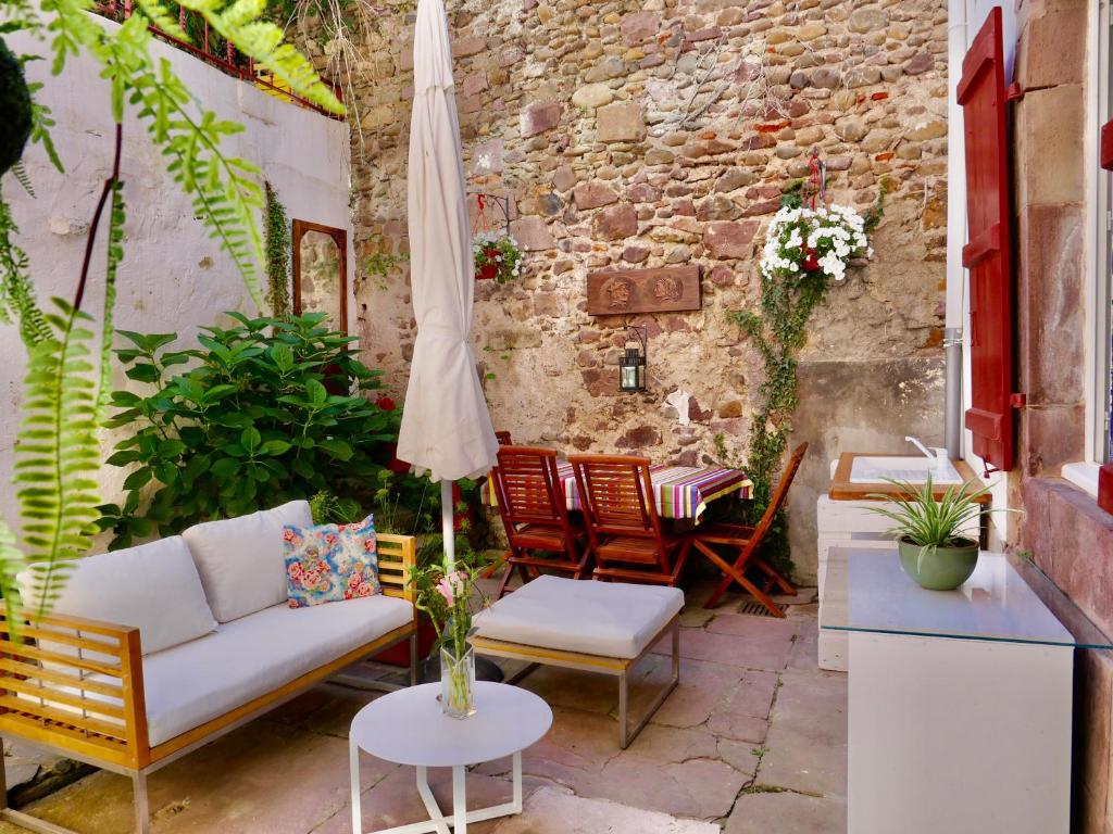 a patio with a couch and chairs and an umbrella at Studio Camino Real in Saint-Jean-Pied-de-Port