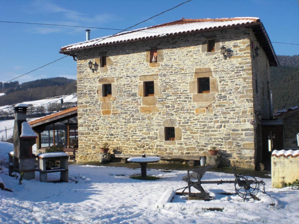 un edificio de piedra con una mesa en la nieve en Casa Rural Pikatzaenea, en Sopuerta