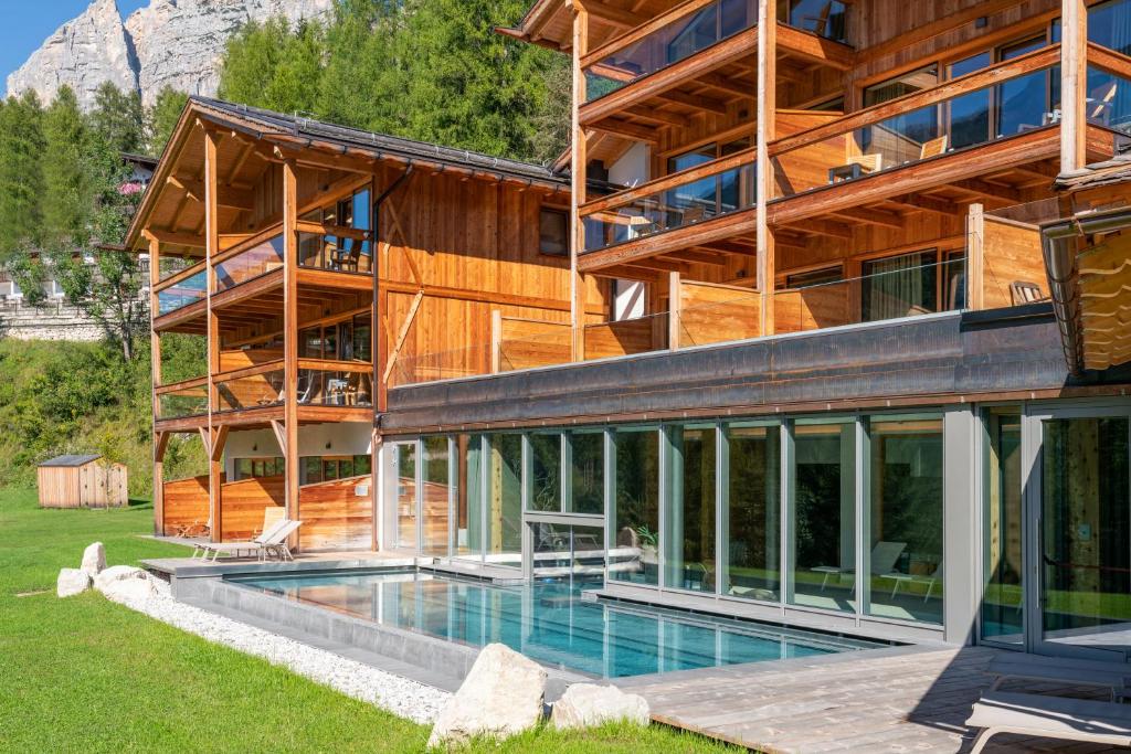 dom z basenem przed nim w obiekcie Dolomiti Lodge Alverà w mieście Cortina dʼAmpezzo