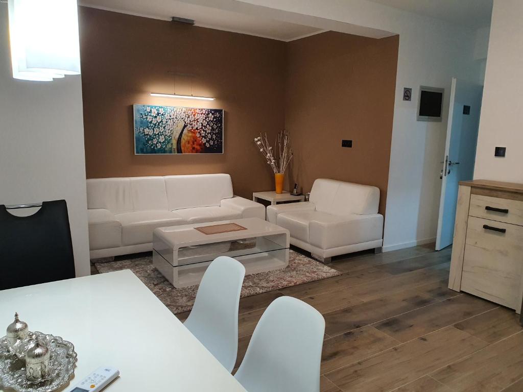 a living room with white furniture and a table and chairs at Apartmani Gandi in Bihać