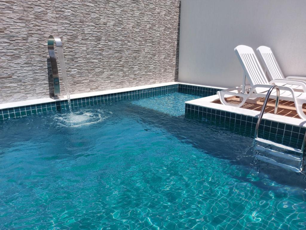 a pool with two chairs and a swimming pool at Casa Barra de São Miguel 4 quartos - BarraMar in Barra de São Miguel