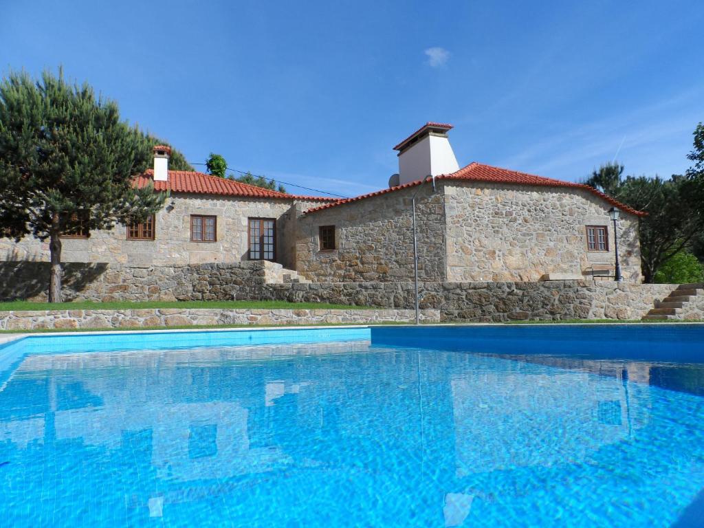 a large swimming pool in front of a stone house at Casa de Panque in Barcelos