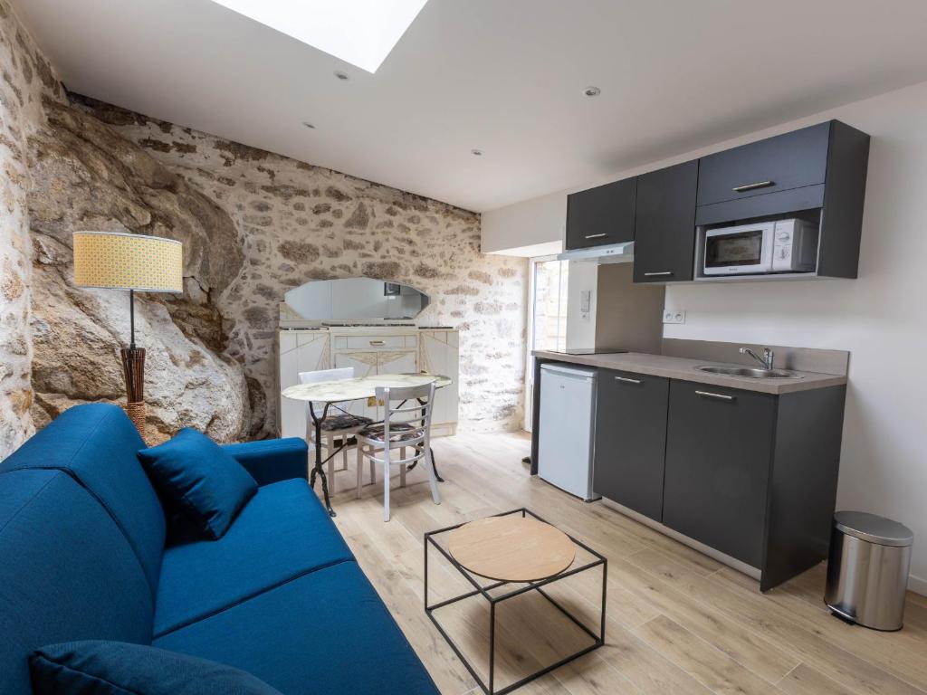 ein Wohnzimmer mit einem blauen Sofa und einer Küche in der Unterkunft Gîte Mortagne-sur-Sèvre, 1 pièce, 2 personnes - FR-1-426-484 in Mortagne-sur-Sèvre