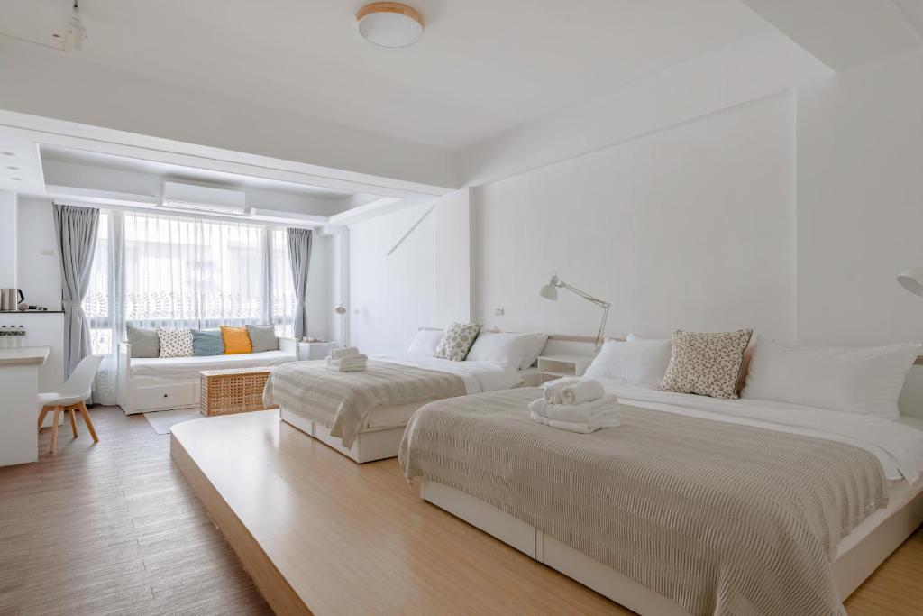 1 dormitorio blanco con 2 camas y sofá en 藍色知更鳥旅宿 en Hualien