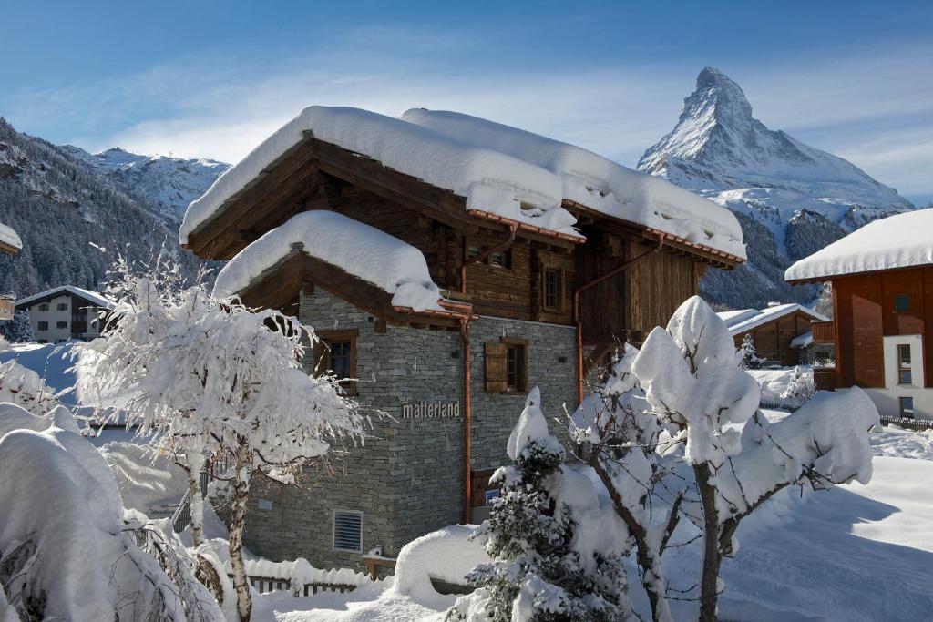 un bâtiment recouvert de neige avec une montagne en arrière-plan dans l'établissement Chalet Matterland, à Zermatt