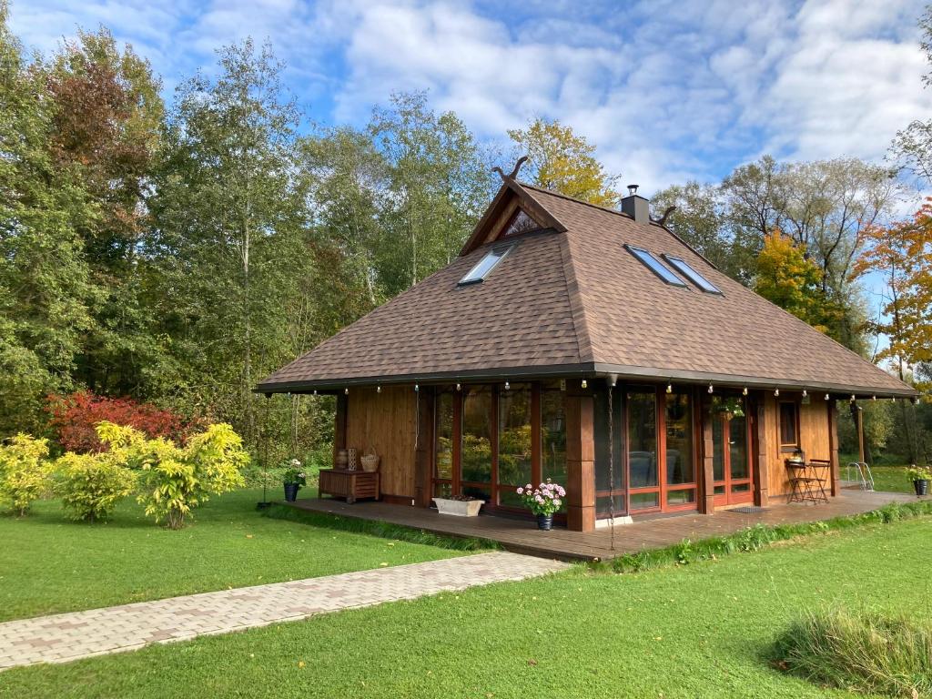 a large wooden house with a gambrel roof at UpeNes in Lubāna