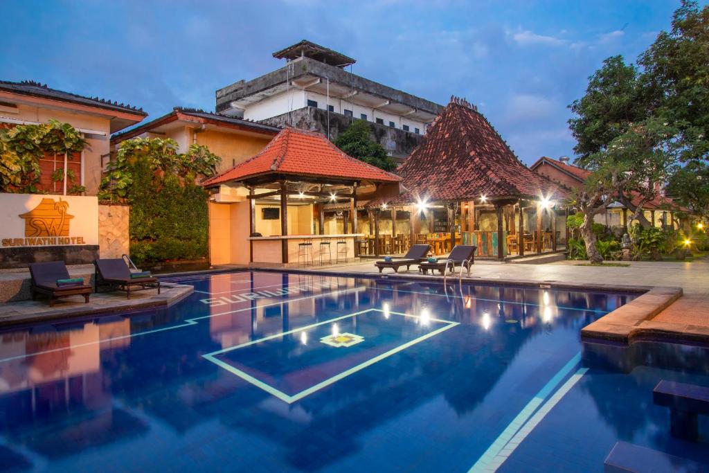 a swimming pool in front of a house with a building at Suriwathi Hotel Legian in Legian
