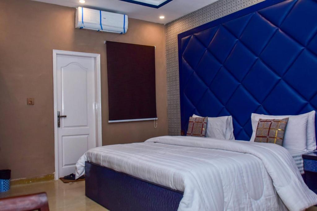 a bedroom with a large bed with a blue headboard at Clifton Rezidor in Karachi
