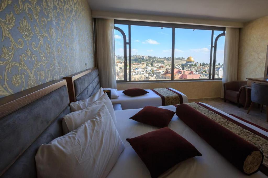 エルサレムにあるハシミ ホテルのベッド2台と大きな窓が備わるホテルルームです。