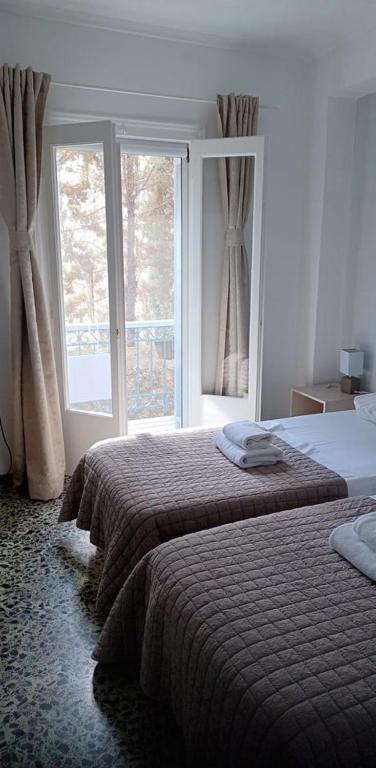 a bedroom with two beds and a large window at Argonaftis Spetses in Spetses