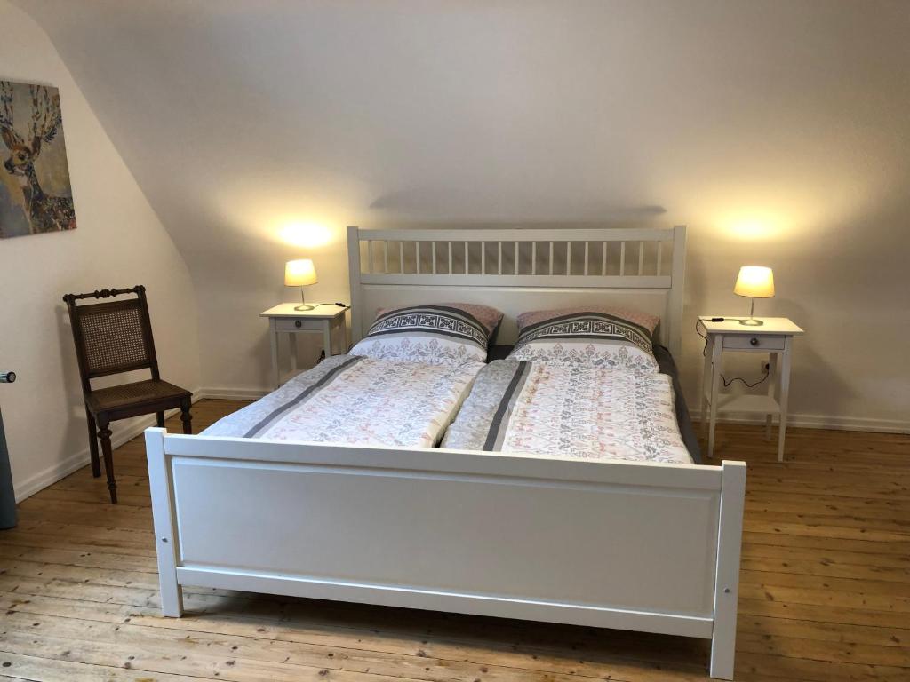 a white bed in a room with two tables and a chair at Haus Blum in Weisweil